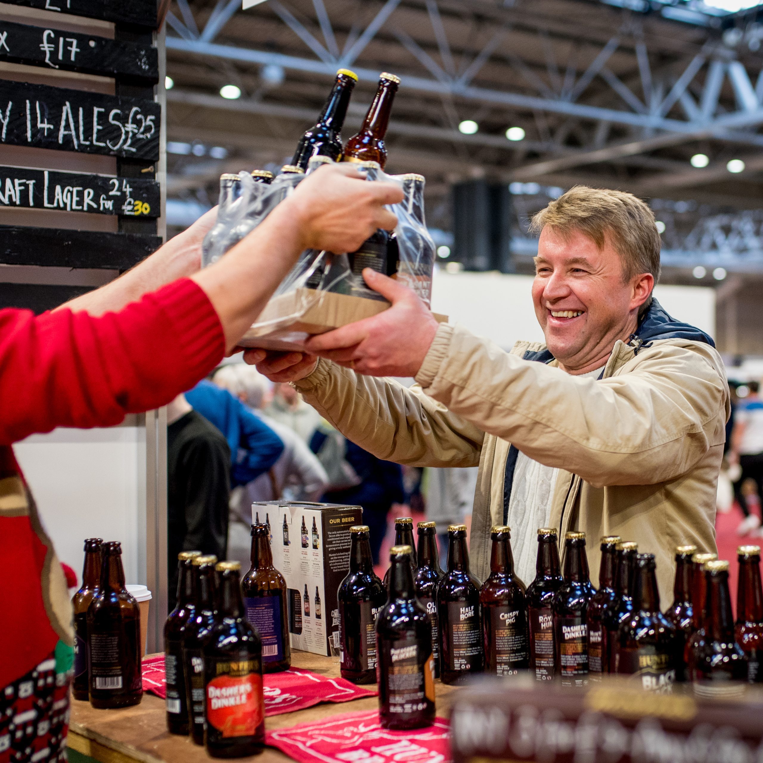 Exchange of a shrinkwrapped tray of beer bottles being passed between exhibitor and customer