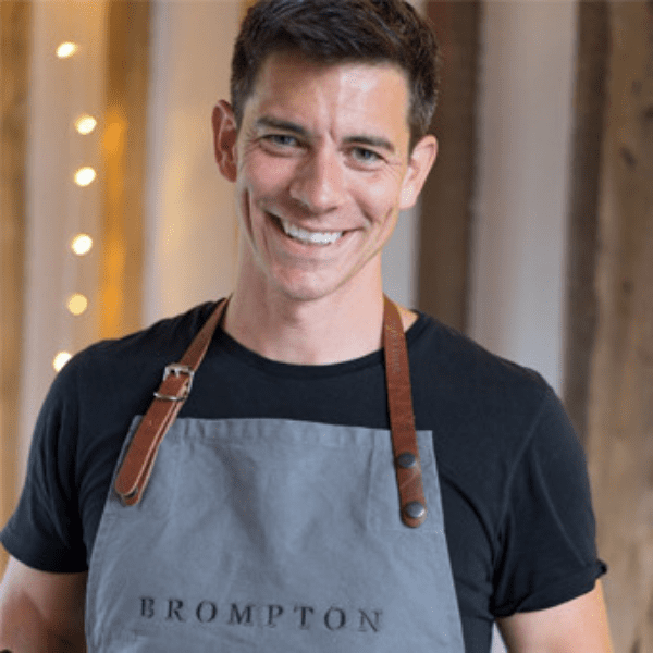Marcus Bean smiling at the camera wearing an apron